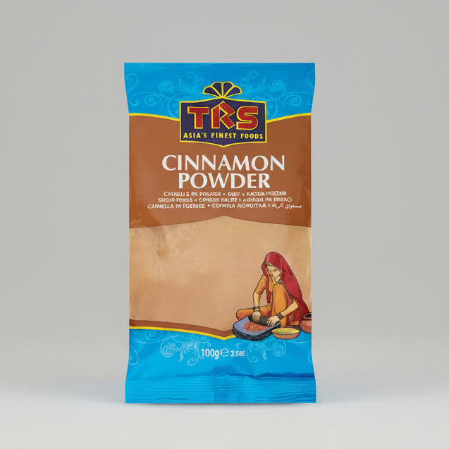 A 100g bag of TKS Cinnamon Powder, featuring a brown and blue packaging design with a traditional illustration of a woman preparing cinnamon.