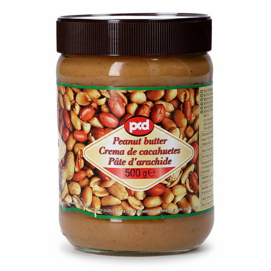 A 500g glass jar of Ptd Peanut Butter with a dark brown lid and a colorful label showing peanuts, containing smooth peanut butter.