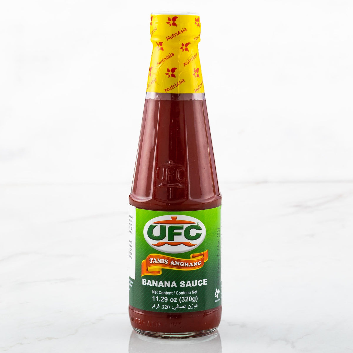 A bottle of UFC Taner Anguano Banana Sauce on a light marble surface with a white background.