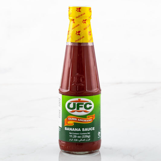 A bottle of UFC Taner Anguano Banana Sauce on a light marble surface with a white background.